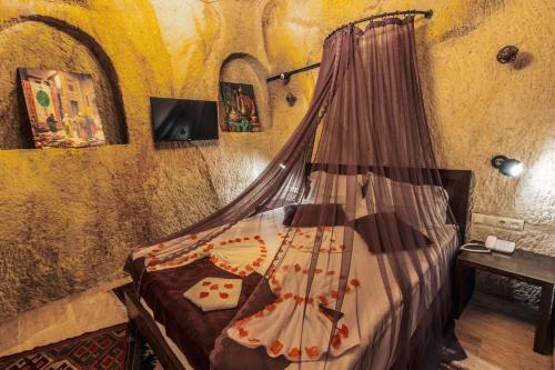 a bedroom with a bed with a canopy in a room at Tafana Cave & Stone Lodge in Urgup