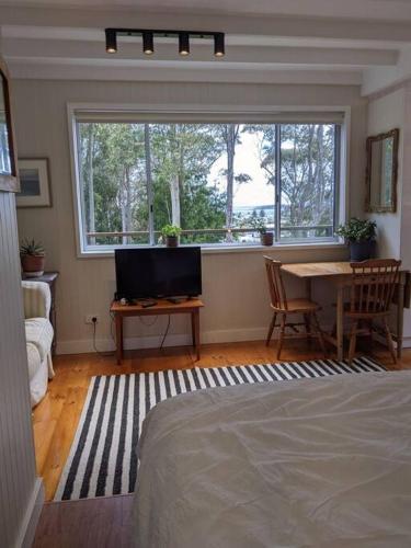 a bedroom with a bed and a desk and a window at Seascape Studio in Tomakin