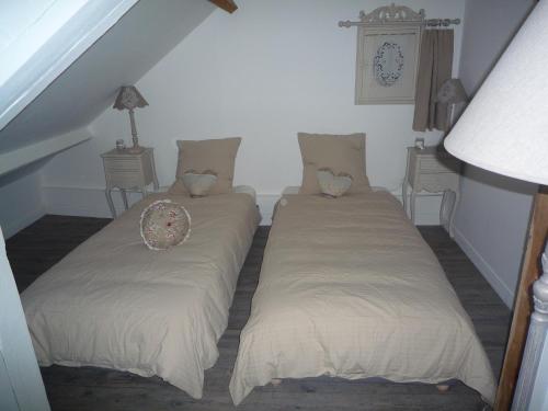 two twin beds in a room with a clock on the wall at Gite du Moulin des Noues in Saint-Germain-sur-École