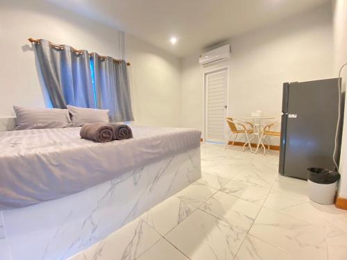 a white bedroom with a bed and a table at บ้านพรธรณีรีสอร์ทเขาใหญ่บ้านสไตล์นอร์ดิก-Baan Ponthoranee Resort Khao Yai in Ban Khlong Yang