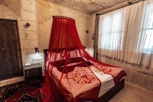a bedroom with a bed with a red mosquito net at Tafana Cave & Stone Lodge in Urgup