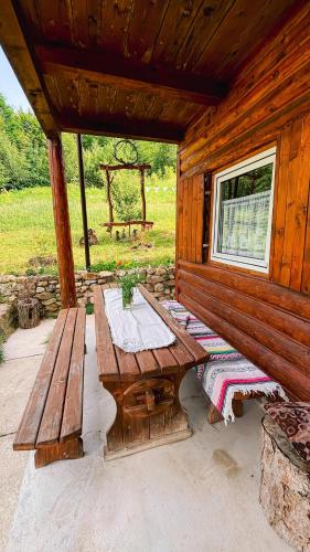 a wooden cabin with a picnic table and a bench at Cabana Trei Brazi Cacica in Cacica