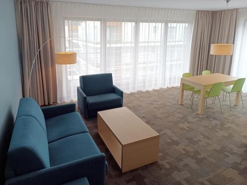 a living room with a couch and a table and chairs at Golden Tulip Międzyzdroje Residence in Międzyzdroje