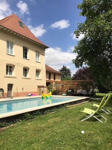 une piscine avec 2 chaises longues et une maison dans l'établissement Escapade romantique dans une demeure du 18ème, à Buchères
