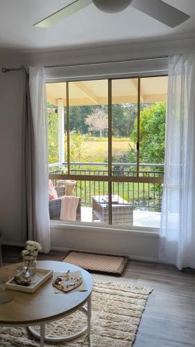 a living room with a table and a large window at Amamoor - Living Waters in Amamoor