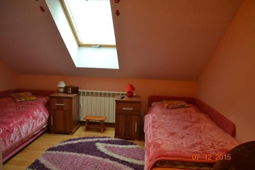 a attic bedroom with two beds and a window at Pokoje Gościnne Na Skraju Lasu in Kamieniec Ząbkowicki