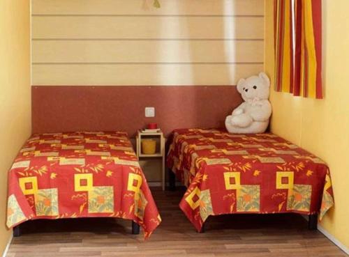 a room with two beds and a teddy bear sitting between them at Camping 3 étoiles - Piscine - eeed0b in Bédouès