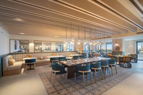een restaurant met een lange tafel en blauwe stoelen bij Palma Bay Rotana Resort in El Alamein