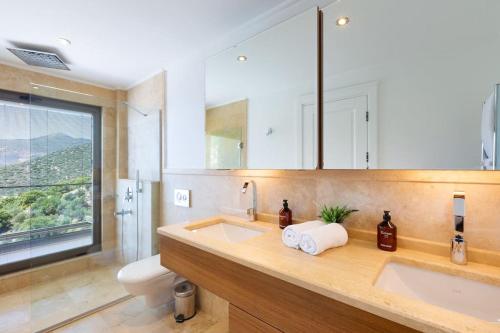 a bathroom with two sinks and a toilet and a window at Villa Korsan- 8 Bedroom Villa with Private Pool and Sea View in Kas