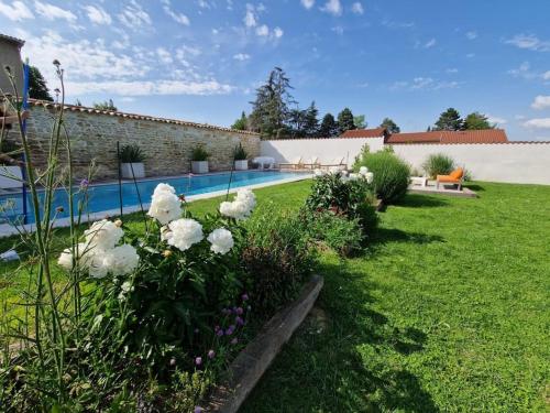un jardin avec des fleurs blanches et une piscine dans l'établissement Domaine de famille Aux deux vieux platanes, à Saint-Germain-au-Mont-dʼOr
