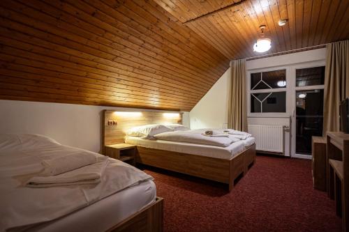 two beds in a room with a wooden ceiling at Penzión Lomnicky in Stará Lesná