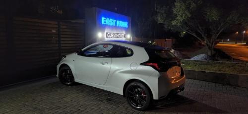 a small white car parked on a street at night at East Park Inn in Polokwane