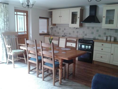 uma cozinha com uma mesa de madeira e cadeiras em Angate Cottage em Wolsingham