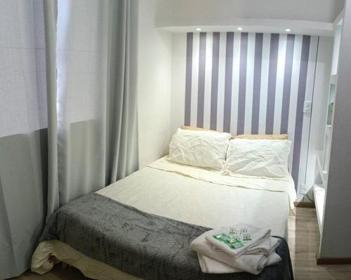 a small bedroom with a bed with a striped headboard at Apartamento Studio no centro de São Lourenço in São Lourenço