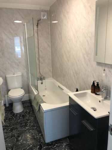 a bathroom with a tub and a toilet and a sink at Town Centre Apartment in Eastbourne