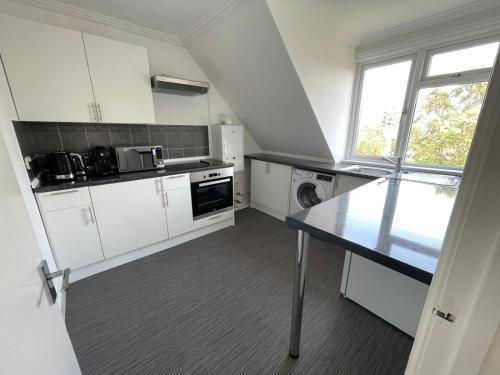 a kitchen with white cabinets and a black counter top at Town Centre Apartment in Eastbourne
