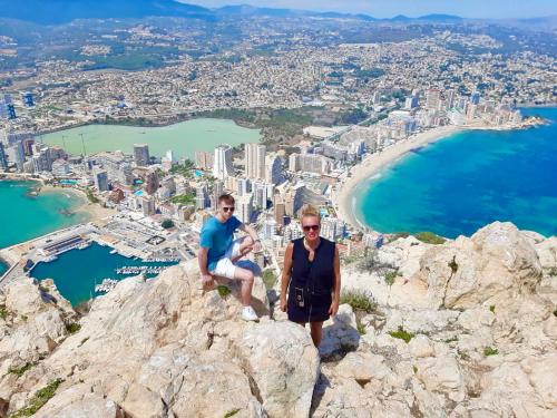 a man and a woman sitting on top of a mountain at VISTA SUPERIOR hola ZEEZICHT!! in Cumbre del Sol