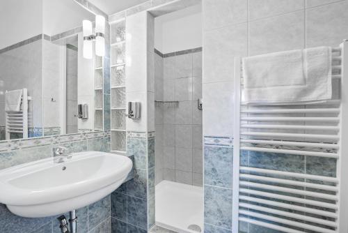 a white bathroom with a sink and a shower at Penzion Sirius in Vyškov