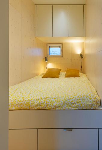 a bed in a small room with two pillows at Vlinder - Ecohuisjes Terschelling in Midsland