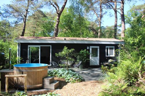 a black tiny house with a hot tub in the yard at Mooi 4p Wellness chalet in het Bos met finse Sauna en Hottub in Diever