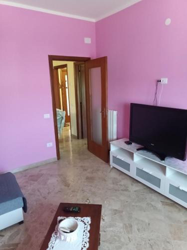 a living room with pink walls and a flat screen tv at affittacamere girasole in Montesarchio