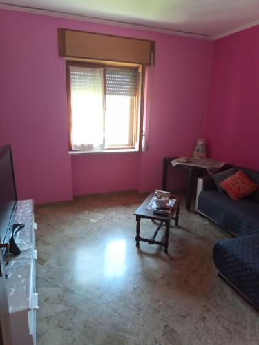 a living room with pink walls and a couch and a table at affittacamere girasole in Montesarchio