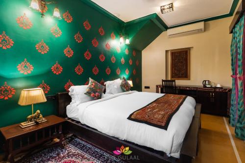 a bedroom with a bed and a green wall at The Gulaal in Jaisalmer