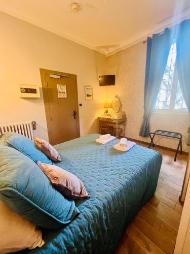 a bedroom with a bed with blue sheets and pillows at Hotel Le Ponteil in Antibes