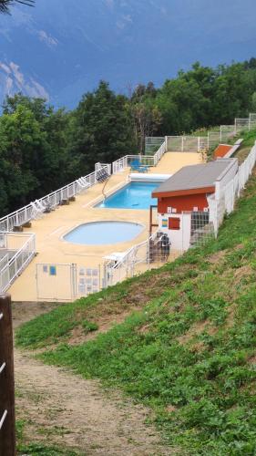 une piscine sur une colline à côté d'une clôture dans l'établissement Oursblanclogis206 Appartement 4 personnes Centre Valmeinier 1800, à Valmeinier