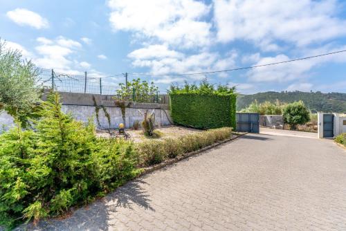 a brick driveway with a hedge and bushes at Quinta da Bela Vista - Ericeira in Galiza