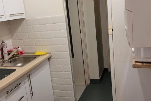 une petite cuisine blanche avec un évier et un couloir dans l'établissement sam34, à Montpellier