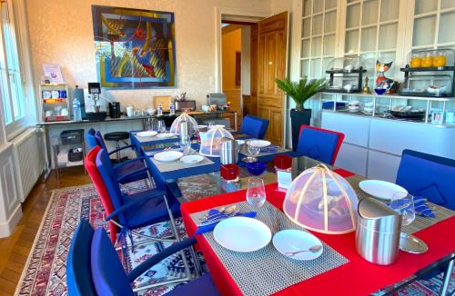 a dining room with a red table and blue chairs at Chateau de Bellevue B&B et Appartements avec Piscine saisonal chauffée et Chambres partout climatisées in Saint-Avit