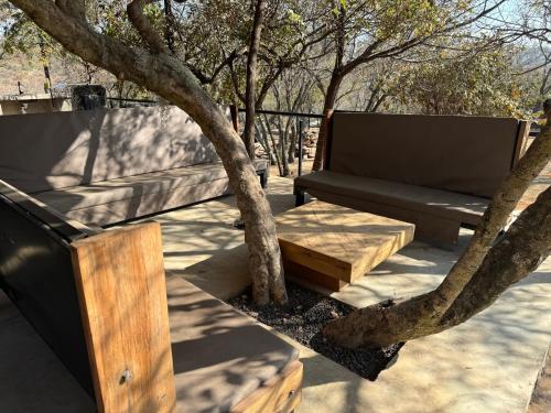 a bench and a table next to a tree at Nectar Game Lodge in Buffelspoort
