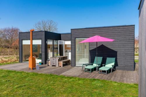 a house with two chairs and a pink umbrella at Sterrenkijker - Ecohuisjes Terschelling in Midsland