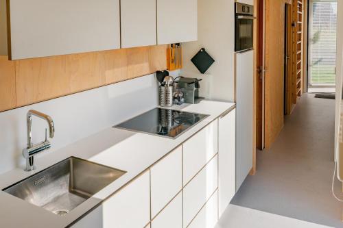 a kitchen with white cabinets and a sink at Sterrenkijker - Ecohuisjes Terschelling in Midsland