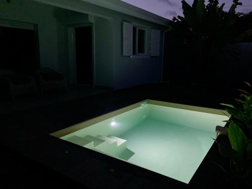Una vista nocturna de una piscina en la oscuridad. en Villas Makandja - plage à 3 min à pied, piscines et jardins privés, en Sainte-Anne
