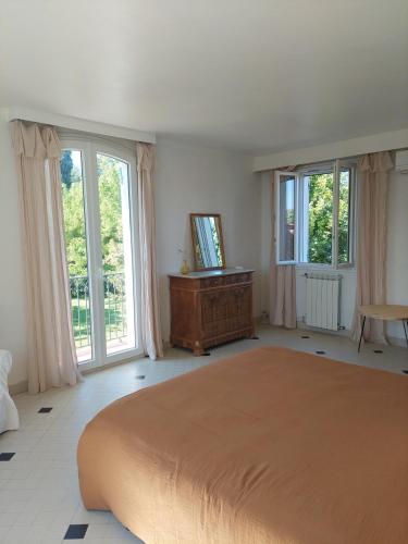 une chambre avec un grand lit et de grandes fenêtres dans l'établissement La maison des Alpilles, à Saint-Étienne-du-Grès