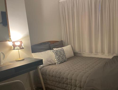 a small room with a bed and a table with a lamp at Bavaria Boutique Hotel in Auckland