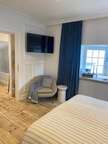 a bedroom with a bed and a chair and a television at Hotel Villa Verdi in Knokke-Heist