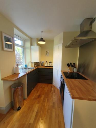 a kitchen with white cabinets and a wooden floor at Cosy 2 bed cottage in Stamford in Stamford