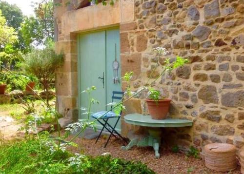 un bâtiment en pierre avec une porte bleue et un banc dans l'établissement Glamping Room The Rose Garden with own garden - external shower & toilet and kitchen, à Mazières