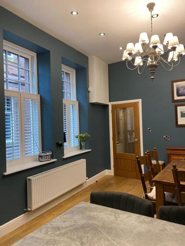 a dining room with blue walls and a chandelier at Cumberland House in Cockermouth