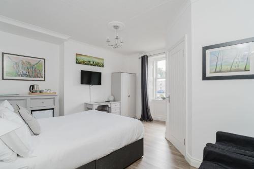 a white bedroom with a bed and a window at The Roxburgh Guest Accommodation in Berwick-Upon-Tweed