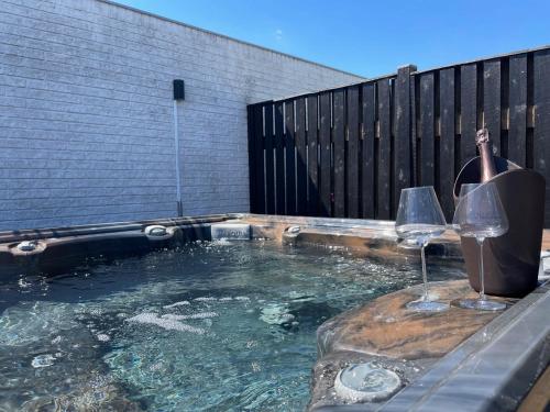 a hot tub with two glasses and a bottle of wine at Wellness House in Frederikssund