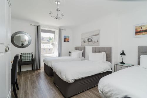 a bedroom with two beds and a chair and a window at The Roxburgh Guest Accommodation in Berwick-Upon-Tweed