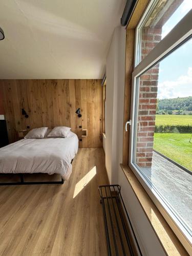 a bedroom with a bed and a large window at La Maison Calestienne in Han-sur-Lesse
