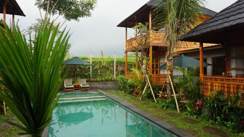 a resort with a swimming pool in front of a house at Harmony Wooden Villas in Ubud