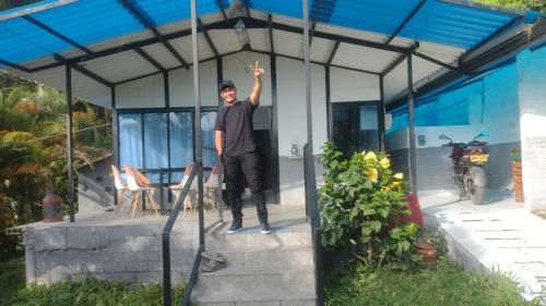 a man standing on the porch of a house at Mi linda casa de campo in Nocaima