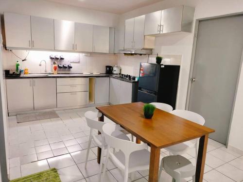 Una cocina con una mesa de madera y gabinetes blancos. en Spacious 3BR Apartment Near Town, en Tuaran