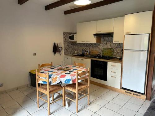 a kitchen with a table and a white refrigerator at Gite les Hortensias in Burzet